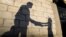 The shadow of a girl receiving a meal for iftar, or the evening meal, to break fast from a member of "Tkiyet Um Ali" humanitarian services center is cast on a wall in front of her family home in the city of Russeif