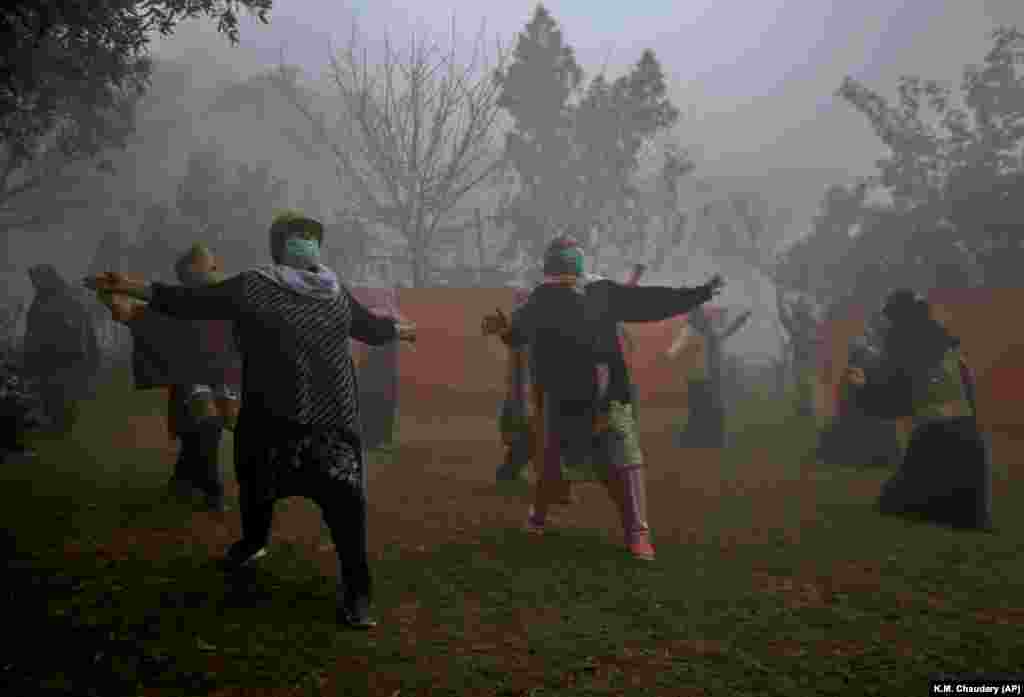 Женщины занимаются йогой в парке во время густого тумана в Лахоре, Пакистан