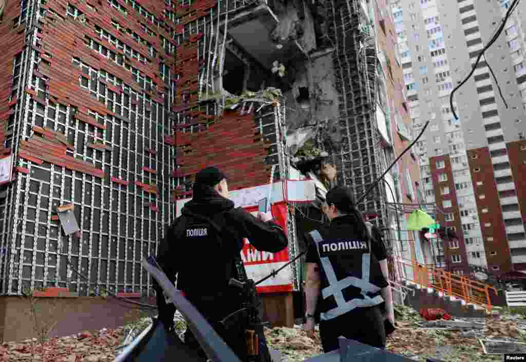 Полицейские стоят возле обломков поврежденного жилого дома на месте удара российского беспилотника на фоне нападения России на Украину в Киеве, Украина, 10 июня 2025 года. REUTERS/Thomas Peter