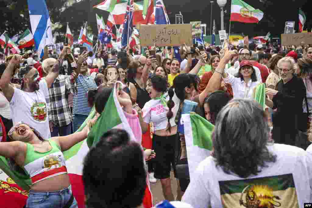 تجمع ایرانیان در سیدنی استرالیا؛ شرکت‌کنندگان با پلاکارد و پرچم شعار می‌دهند.