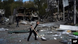 An employee cleans up debris at the remains of a car shop that was destroyed after a Russian attack in Zaporizhzhya on October 11.