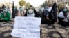 People hold placards as sit-in protests continued in Karachi on January 7 to demand justice following the killings of coal miners from Pakistan's Shi'ite Hazara minority.