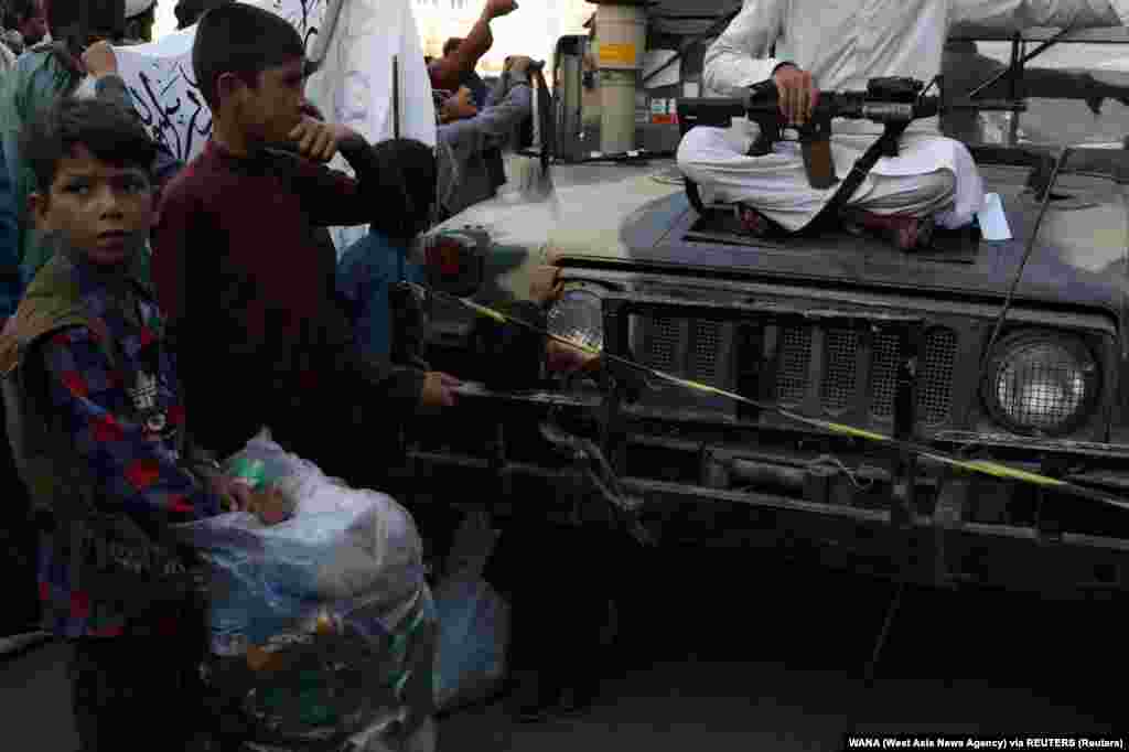 Egy tálib fegyverét nézegeti egy afgán kisfiú Kabulban szeptember 1-jén
