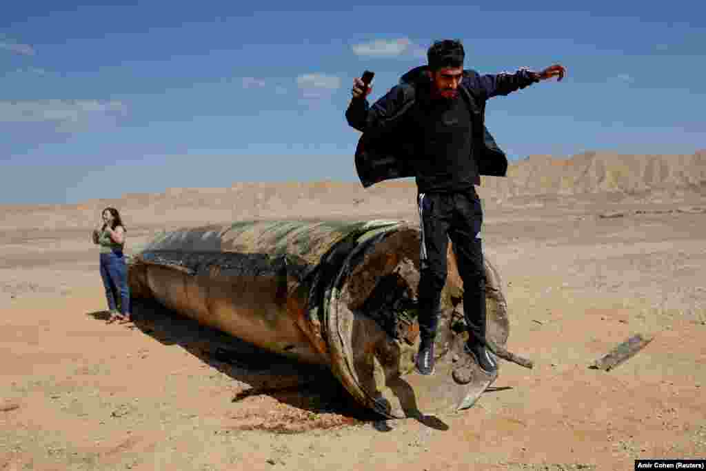 A man jumps off the apparent remains of a ballistic missile lying in the desert, following an attack by Iran on Israel, near the southern Israeli city of Arad.&nbsp;