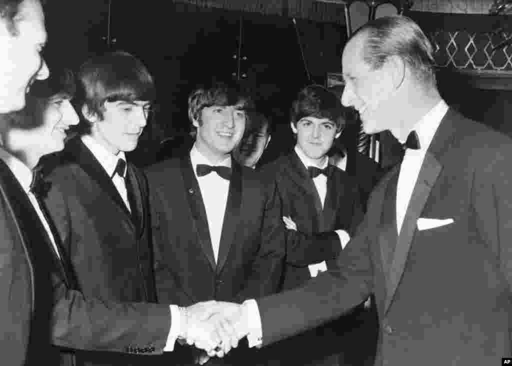 În această fotografie din data de 23 martie 1964, prințul Philip dă mâna cu Ringo Starr în timp ce colegii săi de la Beatles, George Harrison, John Lennon și Paul McCartney, se uită la Empire Ballroom din Londra, Anglia. (AP Photo / File, Pool)