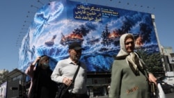 People in Tehran walk past an Iranian propaganda billboard about the Strait of Hormuz on September 16. 