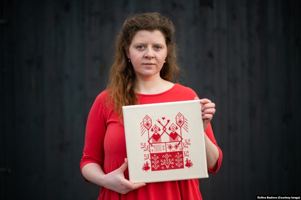 Rufina Bazlova (në fotografi) është artistja bjelloruse me bazë në Çeki që qëndron pas këtij projekti, të cilin e nisi së bashku me historianen e artit, Sofia Tocar.“Framed In Belarus” është një përmbledhje prej 681 punimesh të qëndisura, të realizuara nga vullnetarë nga e gjithë bota, të cilët ndoqën modelet e krijuara nga Bazlova.