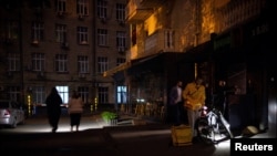 Люди використовують ліхтарики, коли виходять із супермаркету під час часткового відключення електроенергії у Києві, Україна, 16 травня 2024 року