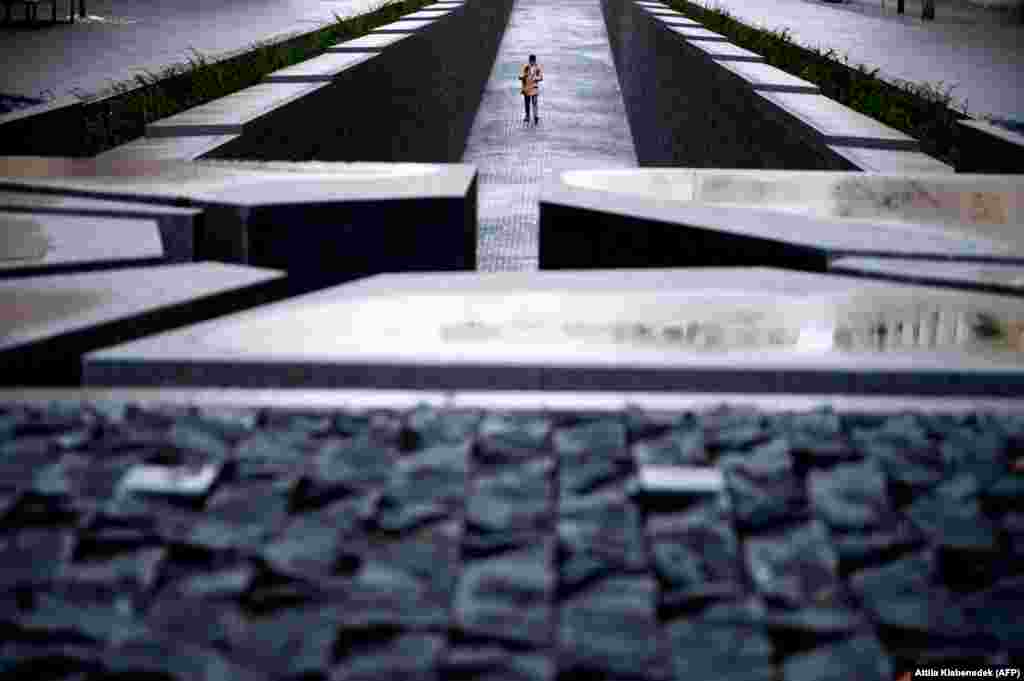 A young visitor wearing a face mask takes photos near the parliament building and the World War I Trianon Memorial in Budapest. (AFP/Attila Kisbenedek)