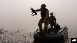  Украински боец скача от лодка на брега на река Днепър на фронтовата линия край Херсон на 15 октомври. 