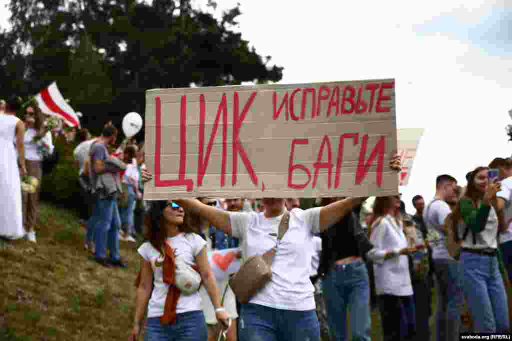 Një protestuese mban një pankartë ku shkruan : &ldquo;(Komisioni Qendror i Zgjedhjeve) rregulloni viruset&rdquo;, një referencë për &ldquo;gabimet&rdquo; e mundshme kompjuterike, që i dhanë fitoren Lukashenkas me 80 për qind të votave.