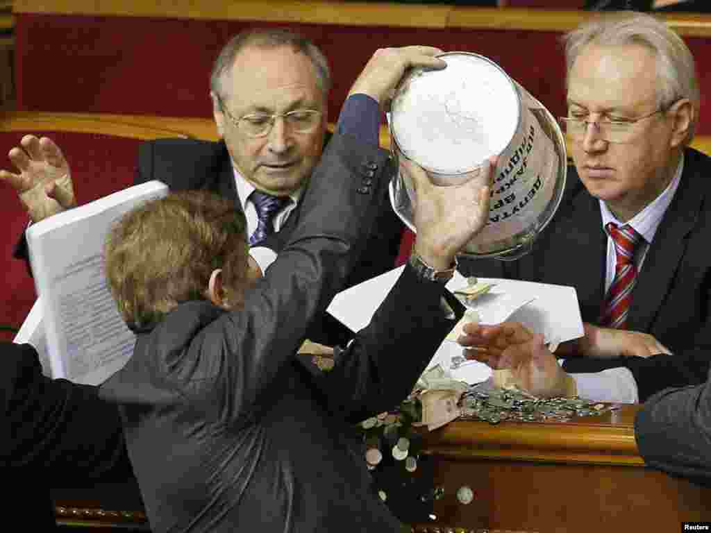 A deputy empties a bucket of change onto the table of Ukrainian government representatives in the chamber of the Ukrainian parliament in Kyiv on November 18. Photo by Sergei Svetlitsky for Reuters