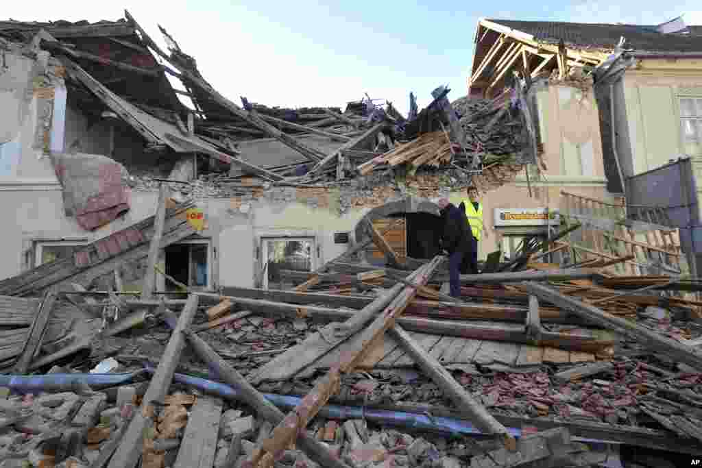 Ljudi prolaze kroz ruševine zgrada oštećenih u zemljotresu u Petrinji u Hrvatskoj, utorak, 29. decembra 2020. (AP Photo)