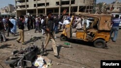 A policeman instructs people to move away from the site of an explosion in Karachi on April 25, 2014