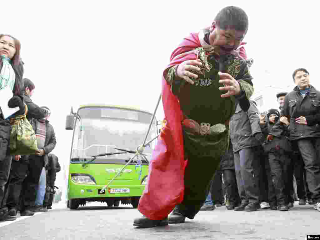 Nurlan Alisherov, a 35-year-old unemployed man, tries to set a bus-pulling record for the &quot;Guinness Book Of World Records&quot; on Ala-Too square in Bishkek on November 28. (REUTERS/Vladimir Pirogov)