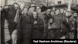 Preživjeli holokausta stoje iza ograde od bodljikave žice nakon oslobađanja nacističkog njemačkog logora smrti Auschwitz-Birkenau 1945. godine.