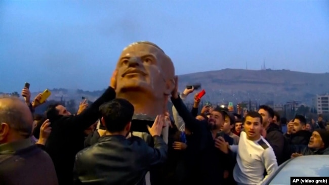 Жители Дамаска празднуют падение режима Башара Асада. В руках у них - голова статуи Хафеза Асада, отца и предшественника свергнутого диктатора