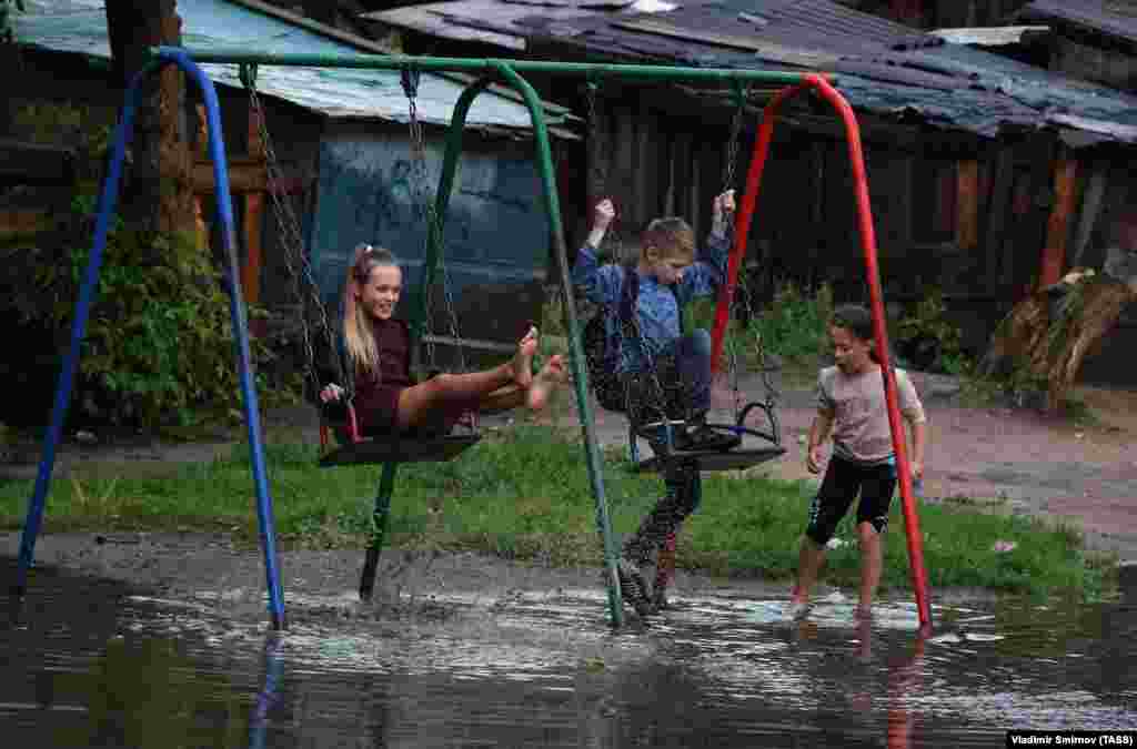 Children play on swings on a flooded playground in the town of Kokhma in Russia&#39;s Ivanovo region. (TASS/Vladimir Smirnov)