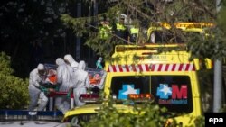 Медики в специальных защитных костюмах перевозят пациента с подозрением на лихорадку Эбола. 