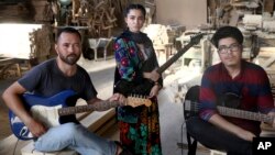 In this Thursday, July 26, 2018, photo, Afghan musicians Mohammad Rezai, right, Hakim Ebrahimi, left, and Soraya Hosseini, members of the Arikayn rock band, pose for a photo at a furniture workshop in Pakdasht, outside Tehran, Iran. The band, made up of A