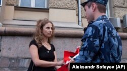 Russian activist of the feminist protest group Pussy Riot Maria Alyokhina talks to a policeman as she holds a protest in front of the FSIN building in Moscow on August 7.