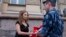 Russian activist of the feminist protest group Pussy Riot Maria Alyokhina talks to a policeman as she holds a protest in front of the FSIN building in Moscow on August 7.