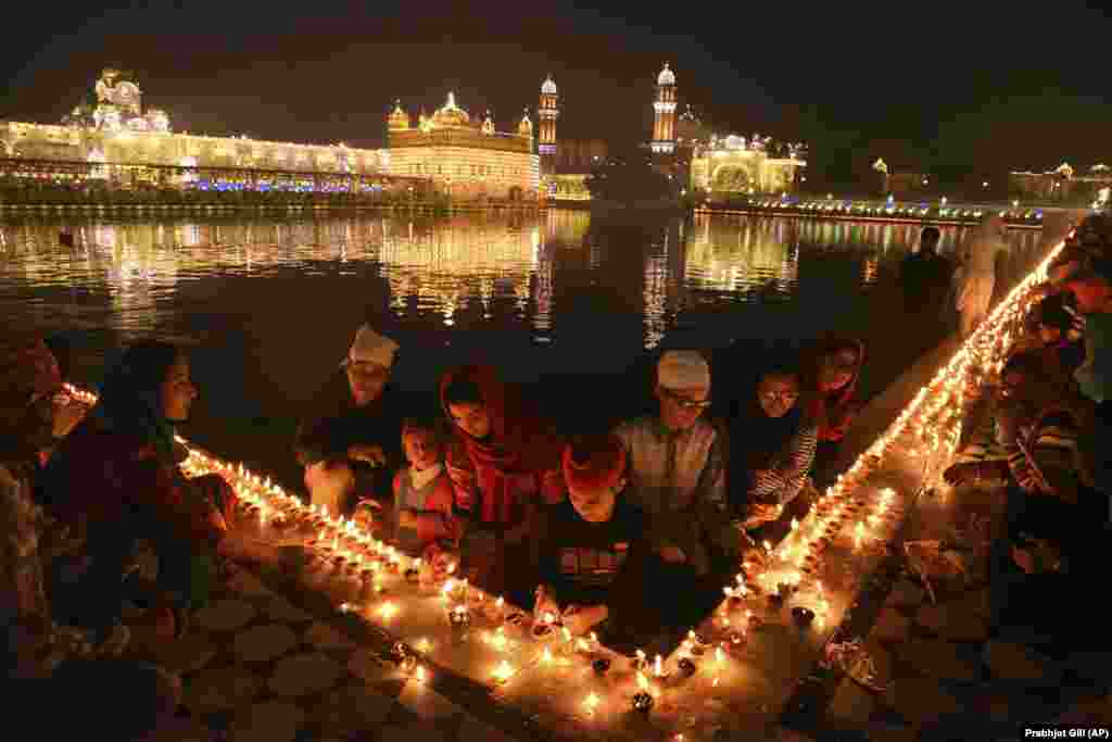 Sikh devotees light candles at the illuminated Golden Temple, the holiest of Sikh shrines, on the birth anniversary of Guru Nanak in Amritsar, India, on November 12. (AP/Prabhjot Gill)