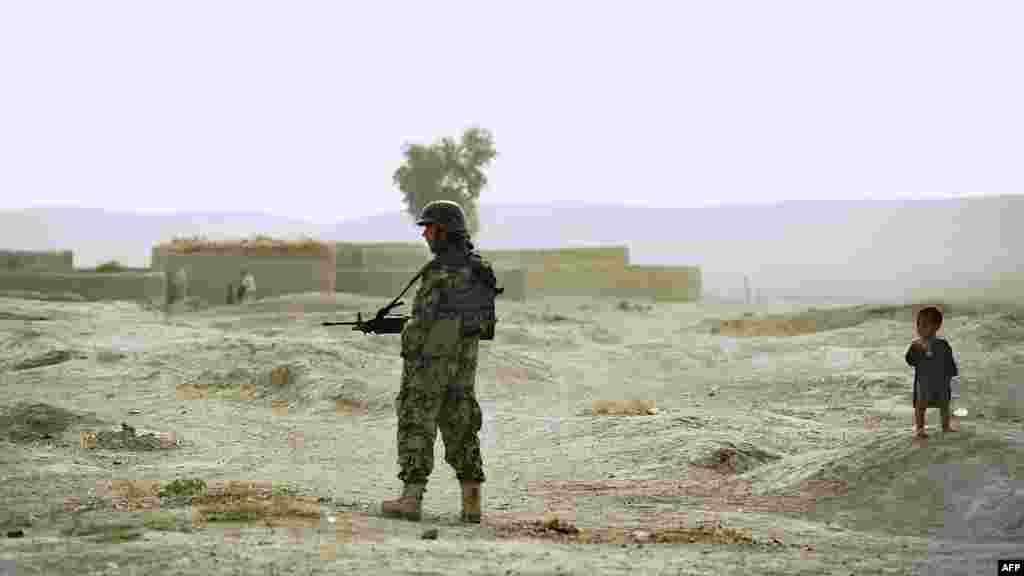 A child looks at a soldier from the Afghan National Army as he secures a perimeter during a joint patrol with U.S. Army soldiers at Nevay-Deh village in Kandahar Province. (AFP/Tony Karumba)