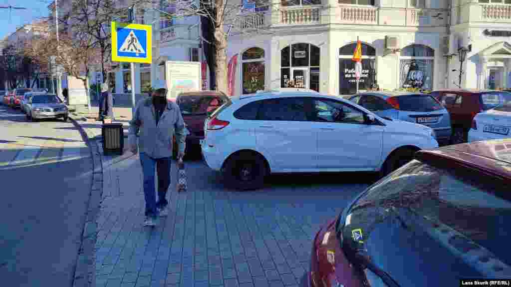Мужчина обходит по краю тротуара припаркованные на проспекте Нахимова автомобили