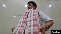 China -- An employee carries bundles of 100 yuan Chinese bank notes to store after counting at a bank in Taiyuan, Shanxi province July 4, 2013. 