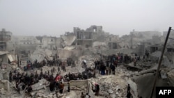 People inspect the destruction following an apparent surface-to-surface missile strike on the northern city of Aleppo on February 19.