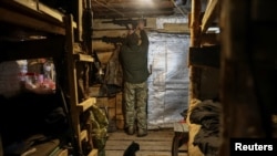 Un soldat ucrainean își îngrijește pușca de asalt într-un adăpost subteran, într-o poziție de pe linia frontului, lângă orașul Kramatorsk (Imagine ilustrativă)