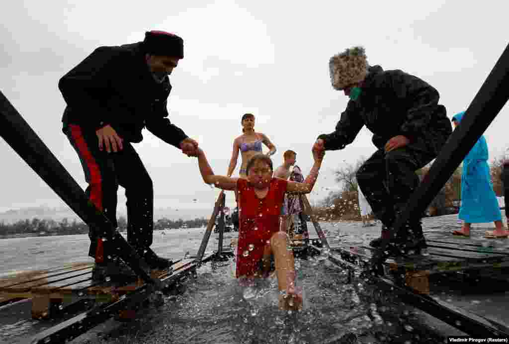 A girl is helped by Cossacks while taking a dip in the village of Leninskoye, Kyrgyzstan.