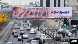 На вуліцах Тэгерану аднавіўся рух транспарту. На банэры з выявамі былых і цяперашніх лідэраў Ірану напісана «Даміно падае», 19 студзеня 2026 году