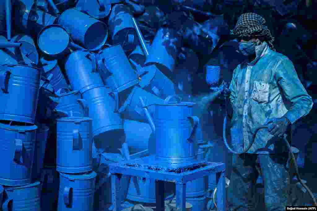 A worker spray paints tin cans at a workshop in Kabul.