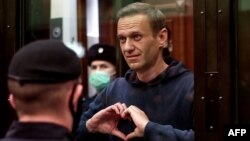 Aleksei Navalny gestures to his wife from inside a glass cell during a court hearing in Moscow in February 2021.