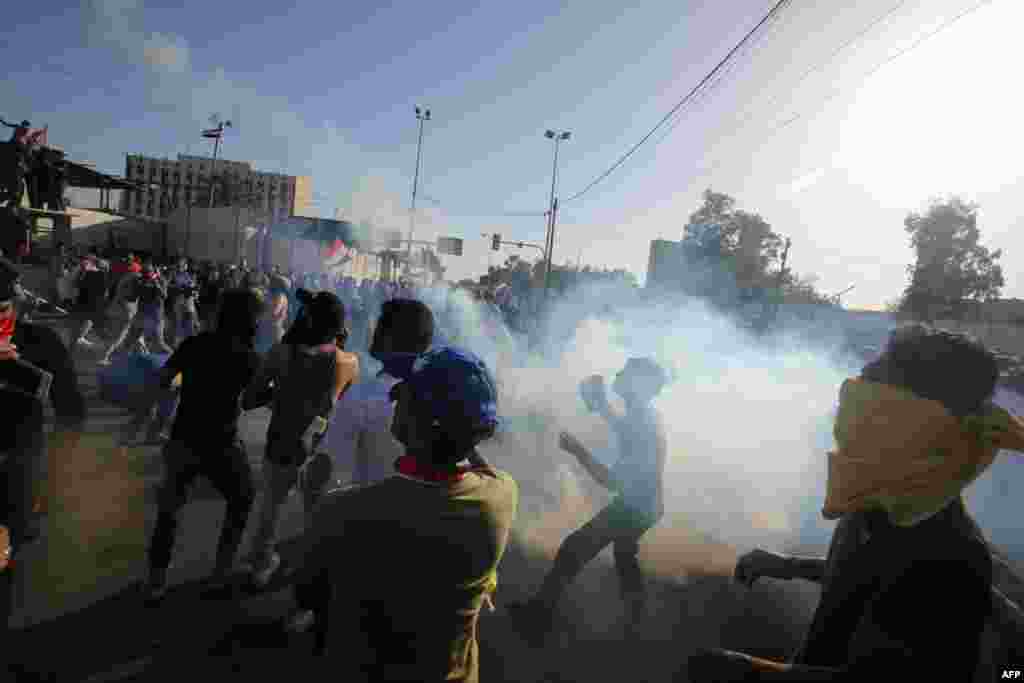 A supporter of Iraqi cleric Muqtada al-Sadr hurls a tear-gas canister back at security forces during clashes after demonstrators broke into Baghdad&#39;s fortified Green Zone on May 20. (AFP/Ahmad al-Rubaye)