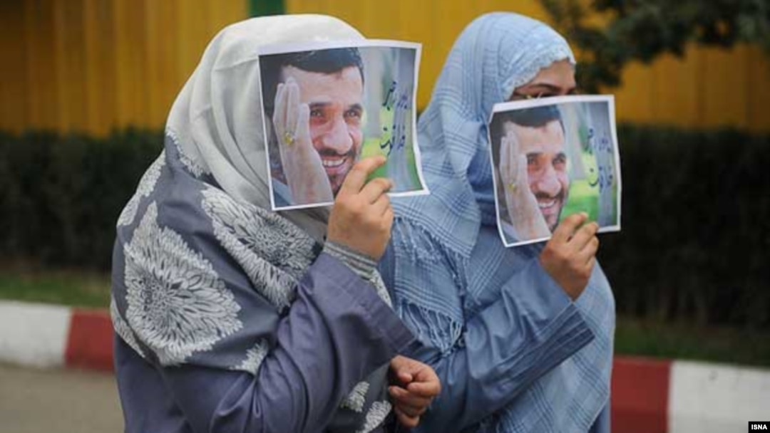 Two women cover their faces with images of Mahmud Ahmadinejad. (file photo)