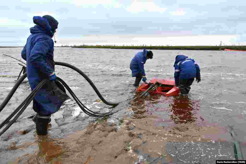 Employees of Russia&#39;s state-owned oil pipeline monopoly Transneft take part in a cleanup operation following May&#39;s massive fuel spill in the Ambarnaya River outside Norilsk.