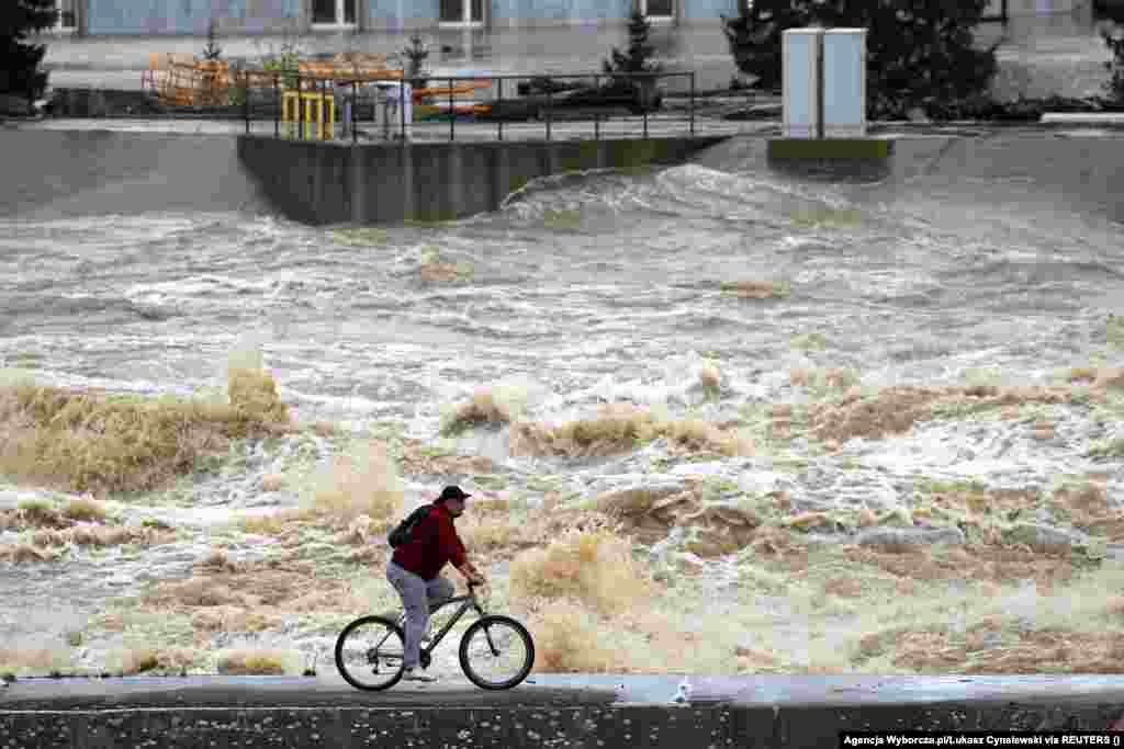 Un bărbat trece cu bicicleta pe lângă apele umflate de lângă centrala hidroelectrică Glebinow din Nysa, Polonia. Două baraje ar fi cedat, în contextul în care autoritățile locale au declarat că situația este &bdquo;critică&rdquo;. &nbsp;