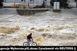 Човек кара велосипед близо до високите нива на водата на река Ниса Клодзка при водноелектрическа централа в Ниса, Полша, 15 септември 2024 г.