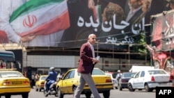 Një burrë kalon një rrugë pranë një billboardi të madh politik përgjatë Sheshit Enghelab në qendër të Teheranit, më 26 maj 2026.