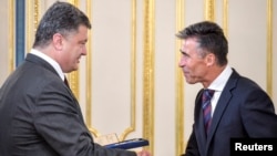 Ukrainian President Petro Poroshenko (left) greets NATO Secretary-General Anders Fogh Rasmussen during their meeting in Kyiv on August 7.