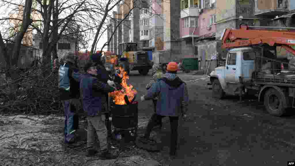 Helyiek melegednek a ház udvarán, amelyet rakétatámadást ért. Makijivka már eddig is megsínylette a háborút. A bombázások miatt gyakori, hogy nincs áram, víz és fűtés