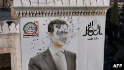 A bullet-riddled portrait of ousted Syrian President Bashar al-Assad hangs over Hama's municipality building after it was defaced following the capture of the city by anti government fighters earlier this month. 