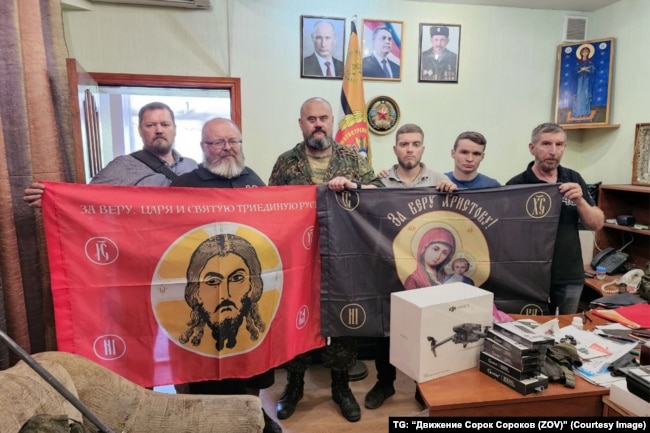 Такія ж сьцягі, што былі заўважаныя ў выкарыстаньні 11-й асобнай гвардзейскай мэханізаванай брыгады, дэманструюць актывісты расейскага радыкальнага праваслаўнага руху «Сорак саракоў» перад адпраўкай разам з дронамі для дапамогі расейскай арміі на вайне з Украінай.