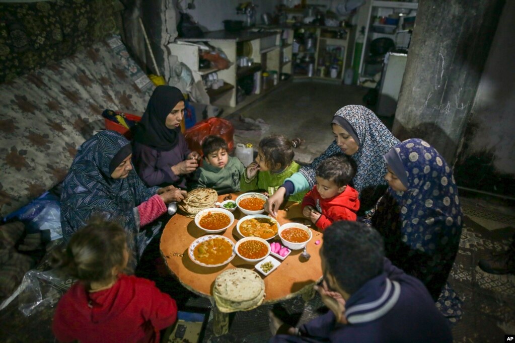 Fatima Al-Absi, majtas, duke ngrënë iftar, shujta pas agjërimit, me vajzën dhe nipërit e saj në ditën e parë të Ramazanit në apartamentin e tyre të dëmtuar në Xhabalia, në veri të Rripit të Gazës, të shtunën, më 1 mars 2025.