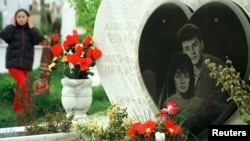 A girl walks past the grave of Admira Ismic and Bosko Brkic, a Muslim-Serb couple buried together after being killed in no-man's land in wartime Sarajevo in 1993.