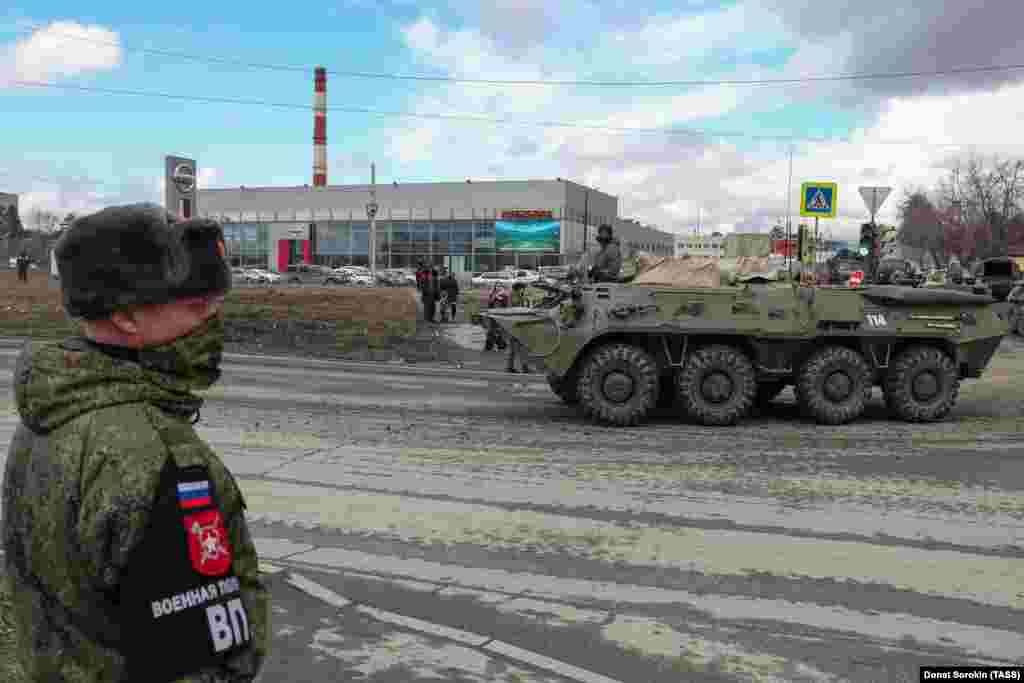 A masked soldier watches a BMP-3 infantry fighting vehicle passing by.&nbsp;