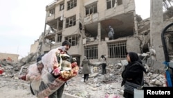 Семейства събират лични вещи от полуразрушена при бомбардировка жилищна сграда в Техеран, 12 март 2026 г.